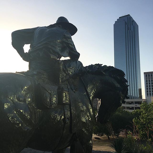A cowboy looking towards the skyscrapers of Dallas